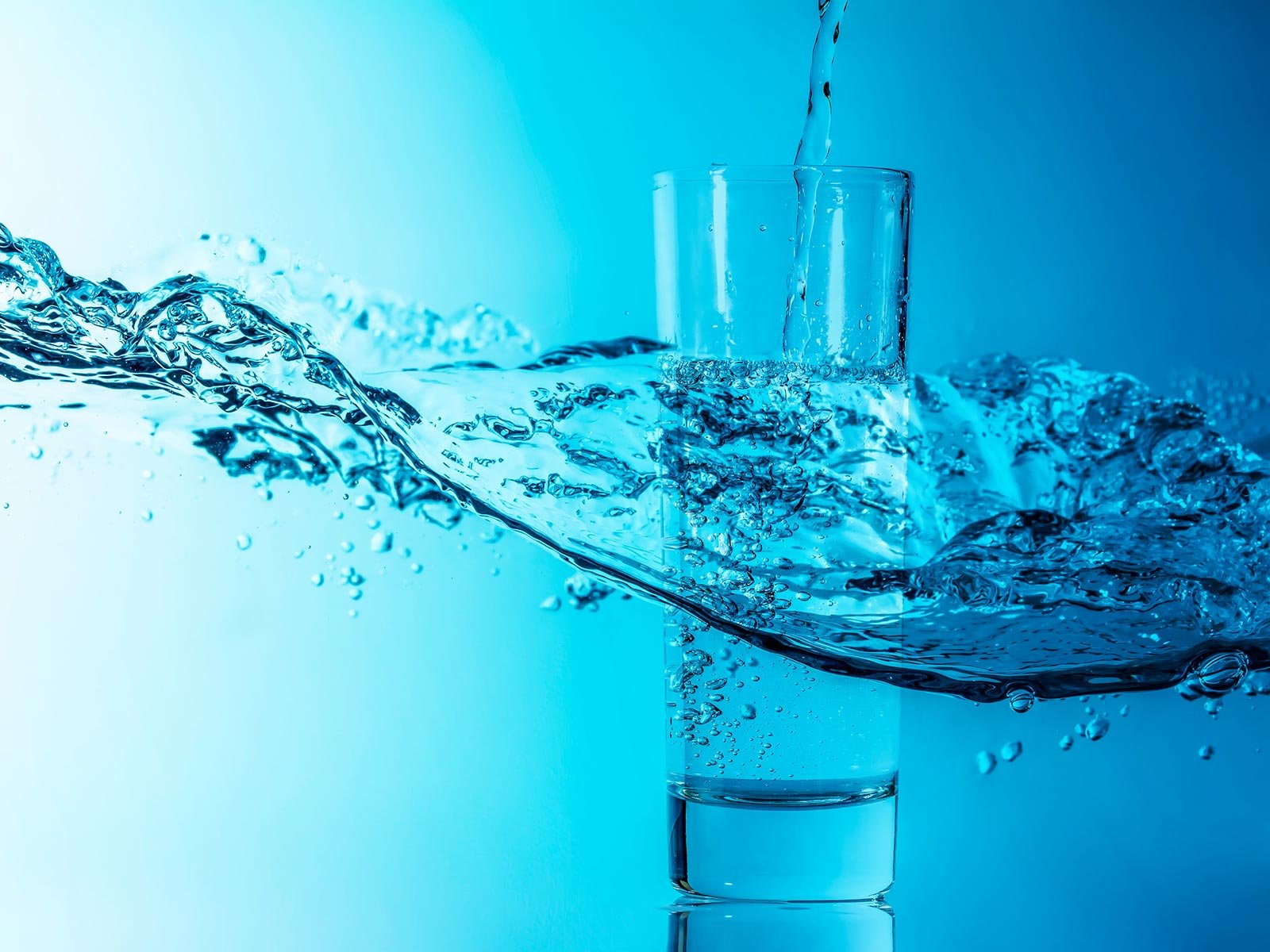 Wasserglas mit Welle vor blauem Hintergrund
