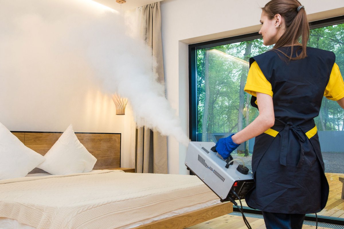 Eine Frau desinfiziert mit Kaltvernebelung ein Hotelzimmer