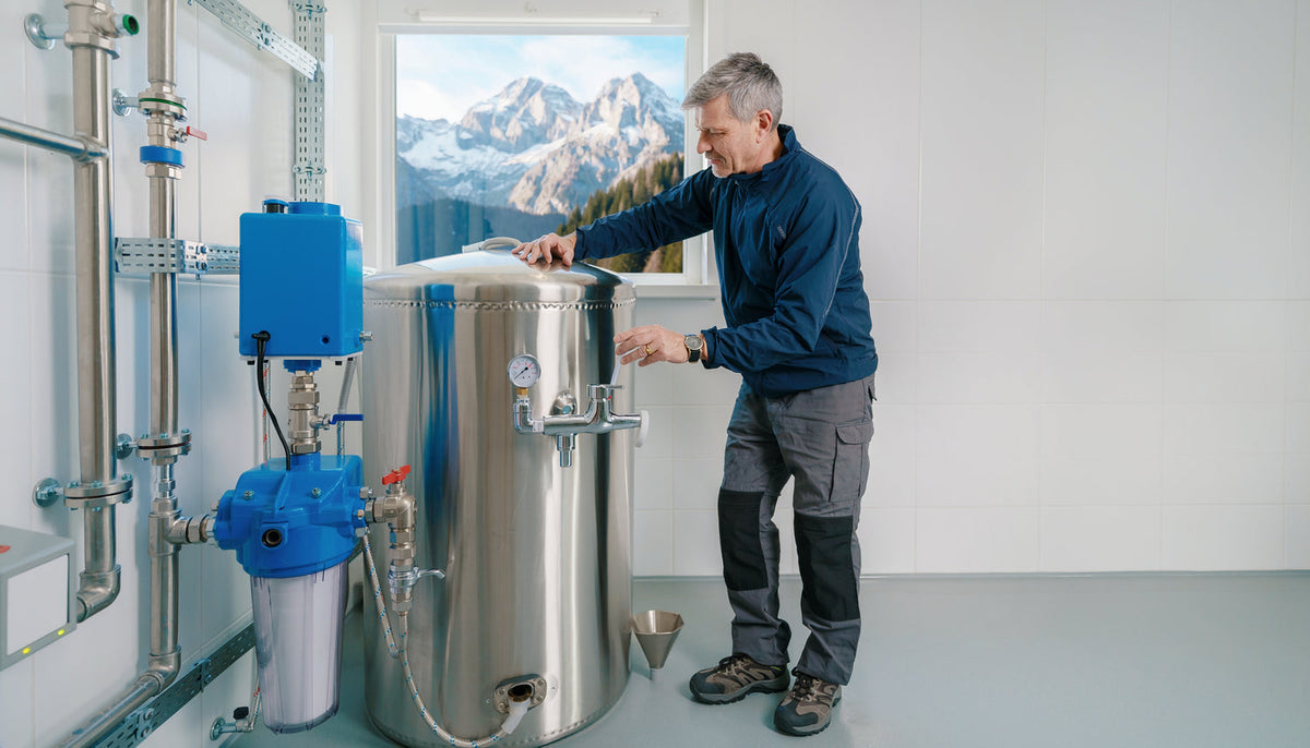Hüttenbetreiber kontrolliert Quellwasser, Speicher und Probenahmestelle einer alpinen Trinkwasserversorgung